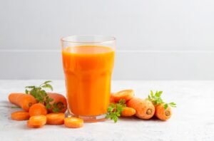 Carrot juice in a glass and fresh carrots